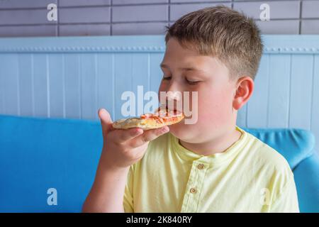 Il ragazzo ama mangiare la pizza. Concetto - obesità e dieta malsana Foto Stock