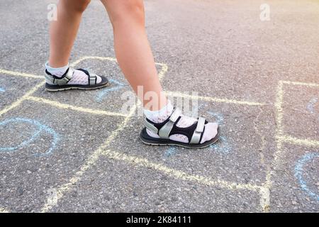 Piedi per bambini e disegni con gesso sul primo piano del marciapiede Foto Stock