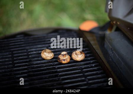 I funghi vengono grigliati. Dettagli picnic. Cibo su grata di acciaio. Cucina in estate. Foto Stock