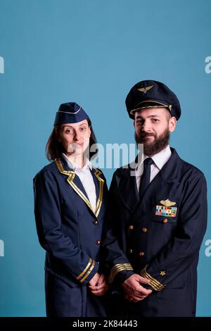 Ritratto dell'aviatore di aeroplano e dell'assistente di volo che indossa l'uniforme di volo, guardando la macchina fotografica, scatto medio. Equipaggio di aviazione professionale, capitano aereo e hostess aereo sorridente Foto Stock