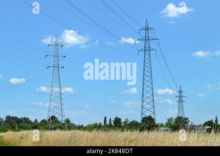 Torri di trasmissione che trasportano linee elettriche ad alta tensione. Tralicci di elettricità nel campo Foto Stock