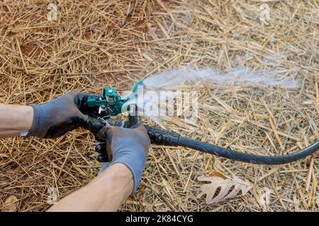 Installazione, manutenzione e irrigazione dell'impianto sprinkler da parte di un tecnico paesaggista professionista vicino a una nuova casa Foto Stock