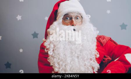 Ragazzo in abito Santa guardando la fotocamera su sfondo stellato. Concetto di feste, regali e feste. Foto Stock