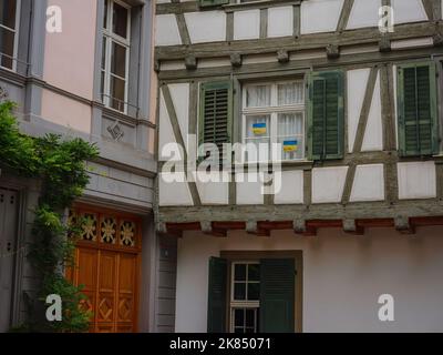 Edifici nel centro di Basilea, Svizzera. La bandiera nazionale dell'Ucraina è appesa nel cortile. Bandiera giallo-blu sulla finestra della vecchia casa Foto Stock