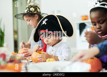 Un gruppo di bambini che puliscono le zucche in una festa. Foto Stock