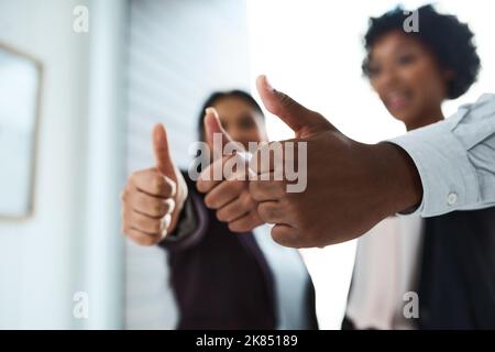 Un gruppo di uomini d'affari irriconoscibili che mostra i pollici in un ufficio. Foto Stock