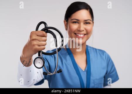 Nonostante tutto, a causa di tutto, im un eroe. Ritratto di un giovane medico che tiene uno stetoscopio su sfondo bianco. Foto Stock