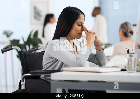 Un po' di brutta giornata. Una giovane e attraente donna d'affari che guarda stressata mentre lavora alla sua scrivania in ufficio. Foto Stock
