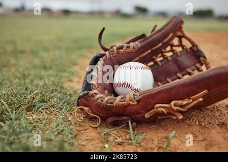 Baseball, palla e guanto su un campo all'aperto per allenamenti sportivi, fitness o una partita di torneo. Esercizio, attrezzature sportive e partita di softball su un Foto Stock