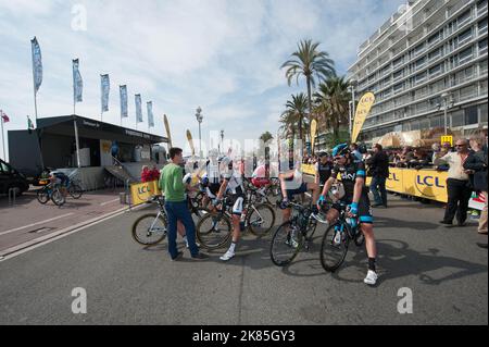 Frank Mathias del team IAM Cycling e Xabier Zandio siedono e chiacchierano sulla linea di partenza con il podio sullo sfondo della Promenade Anglais. Foto Stock