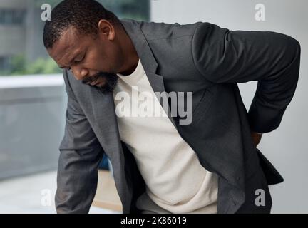 Ho bisogno di una vacanza, un giovane uomo d'affari che vive mal di schiena sul lavoro. Foto Stock