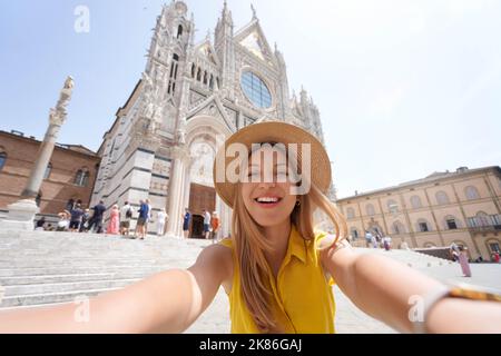 Selfie girl a Siena, Italia. Giovane donna turistica che si autoritratto con la Cattedrale di Siena, Toscana, Italia. Foto Stock