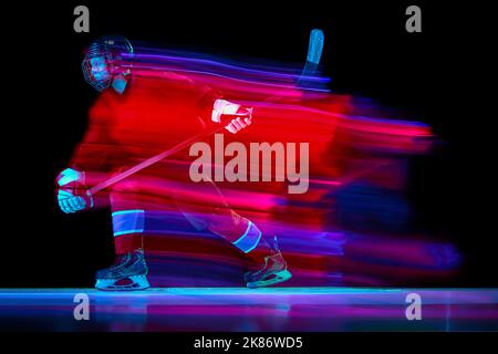 Ritratto dinamico dell'energico allenamento dei giocatori di hockey con bastone isolato su sfondo scuro in una luce al neon mista. Arte, sport, azione, movimento Foto Stock