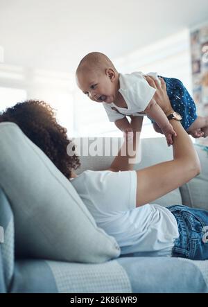 Non riesco a trovare abbastanza di questo taglio. Una giovane donna che si rilassa con la sua adorabile bambina sul divano di casa. Foto Stock