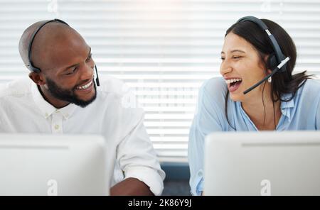 Siamo così bene: Due giovani uomini d'affari seduti in ufficio e indossando cuffie mentre si utilizza il computer. Foto Stock