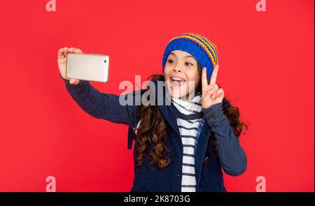 ragazza teen stupita in giù giubbotto con smartphone. ritratto di bambino blogging con telefono. Foto Stock