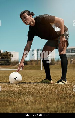 Uomo, piazzamento e pallone da calcio con mano sul campo per calcio, rigore o gol nel gioco, allenamento o partita. Sport, calcio e erba in estate per l'esercizio Foto Stock