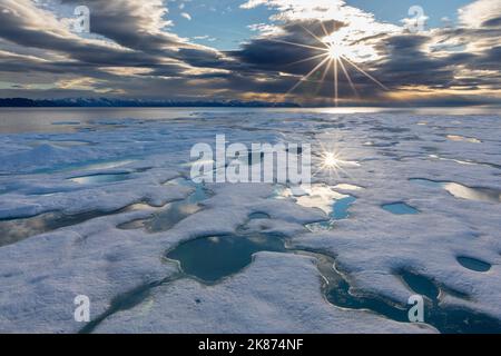 Sunburst su ghiaccio veloce a Lancaster Sound, tra Devon Island e Baffin Island, Nunavut, Canada, Nord America Foto Stock