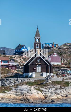 Una vista della Chiesa di Sion circondata da case dipinte di colori nella città di Ilulissat, Groenlandia, Danimarca, regioni polari Foto Stock