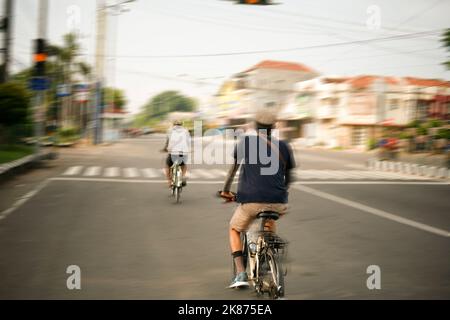 sfocatura del movimento di due persone in bicicletta in strada asiatica Foto Stock