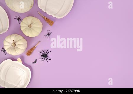 Piatto di Halloween con piatti a forma di zucca, zucche, scopa strega, ragni e bare su sfondo viola con spazio copia Foto Stock