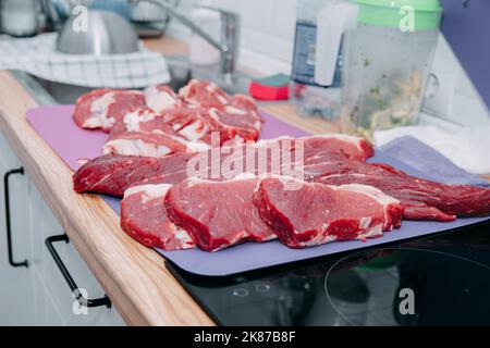 Manzo crudo affettato, preparazione di carne per la cottura della bistecca alla lezione di cucina. Carne cruda su un piatto nero. Foto Stock