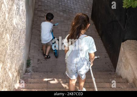 Ragazzo in bicicletta e sua sorella con scooter che scende sulle scale della città. Foto Stock