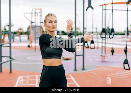 Forte atletica donna allunga i suoi muscoli dopo l'allenamento di forza. Foto Stock