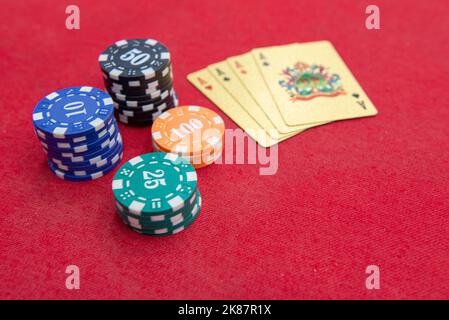 Quattro assi vicino pile di fiches su un tavolo di feltro rosso. Il gioco del poker è uno dei giochi di carte più popolari al mondo e ha giocato molto nei casinò. Scheda Foto Stock