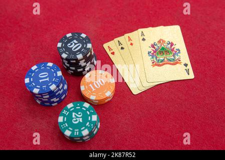 Quattro assi vicino pile di fiches su un tavolo di feltro rosso. Il gioco del poker è uno dei giochi di carte più popolari al mondo e ha giocato molto nei casinò. Scheda Foto Stock