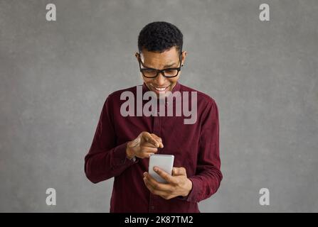 Allegro afro americano ragazzo in stile indossare visualizzare le foto nei social network su cellulare Foto Stock