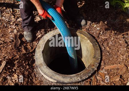 Tubo nel pozzo di drenaggio. Pompaggio di acque reflue da un serbatoio settico. Foto Stock