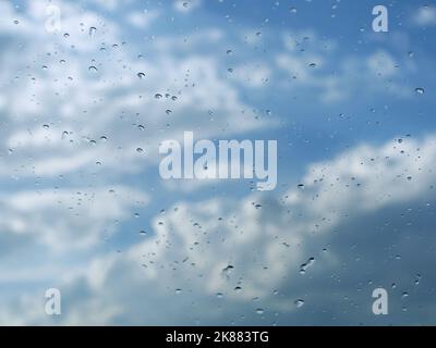 La pioggia cade sul parabrezza con lo sfondo di cielo nuvoloso dopo la pioggia Foto Stock