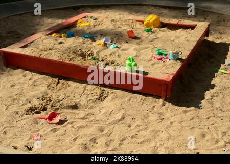 Parco giochi per bambini con sabbia. Sandbox per bambini sulla strada. Posto per i bambini gioco. Sabbia con giocattoli. Giocattoli dimenticati. Foto Stock