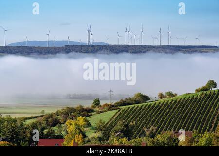 Un gruppo di mulini a vento si erge su una collina contro un cielo limpido e c'è nebbia nella valle di fronte ad essa. Foto Stock