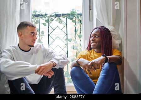 Coppia multirazziale che parla seduto sul pavimento a casa Foto Stock