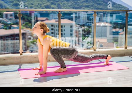 Bella donna fare yoga all'aperto su una terrazza sul tetto Foto Stock