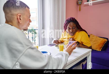 Felice coppia multietnica gustando la colazione a casa Foto Stock
