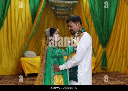 Sposa e Groom alla tradizionale cerimonia Mayoon in un locale decorato con colori vivaci a Karachi, Pakistan Foto Stock