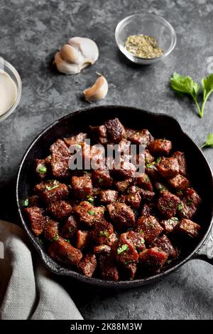 La bistecca all'aglio al burro si morde in una teglia di ghisa su fondo in pietra. Vista ravvicinata Foto Stock