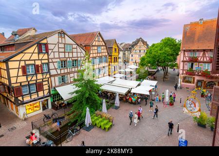 Una strada pittoresca di negozi e caffè lungo il marciapiede nel centro storico medievale di Colmar, in Francia, una delle fermate lungo la strada del vino nella zona dell'Alsazia. Foto Stock