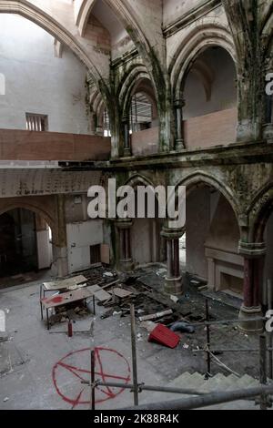 Uno scatto verticale dell'interno di una cattedrale abbandonata con archi e un pentagramma disegnato sul pavimento Foto Stock