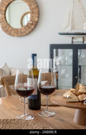 Uno scatto verticale di un paio di bicchieri con vino sull'accogliente tavolo di legno Foto Stock