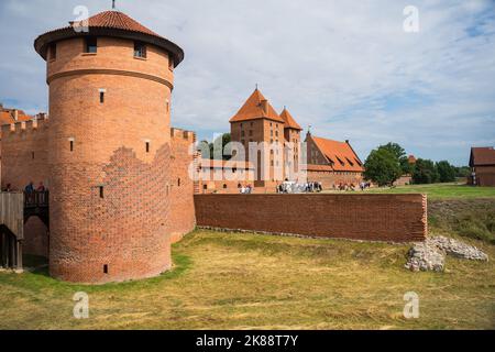 Una vista dei Cavalieri Teutonici catle a Malbork, Polonia con torri di mattoni, tegole tetto e un campo d'erba. Foto Stock