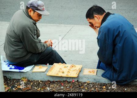 Due anziani asiatici contemplano la loro prossima mossa in una partita di xiangqi all'aperto in un parco fuori città Foto Stock