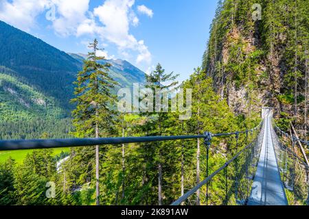 Semplice ponte sospeso sulla valle di montagna Foto Stock