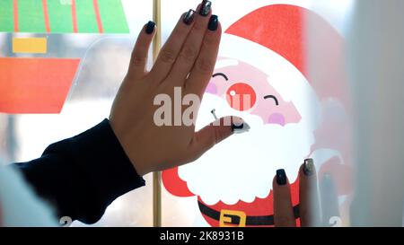 Primo piano, la gente decorare la finestra in casa con decorazioni natalizie, adesivi. Foto di alta qualità Foto Stock