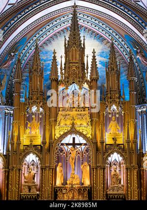 Primo piano della pala d'altare dorata ornata con statue e crocifisso dietro l'altare principale presso la Basilica di Notre-Dame nella Vecchia Montreal, Quebec. Foto Stock