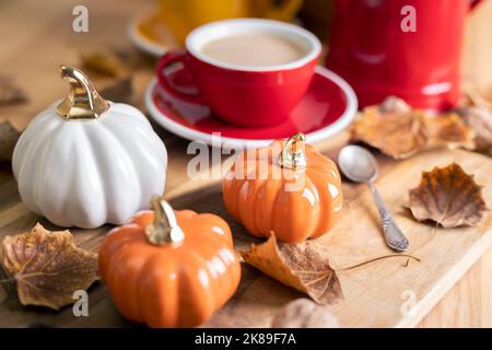 splendido sfondo autunnale con zucche e una tazza di caffè. decorazioni autunnali negli interni Foto Stock