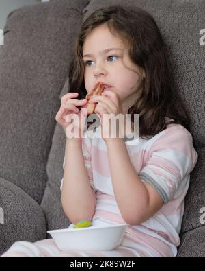 una bella ragazza in un pajama sta mangiando la pancetta per la colazione Foto Stock